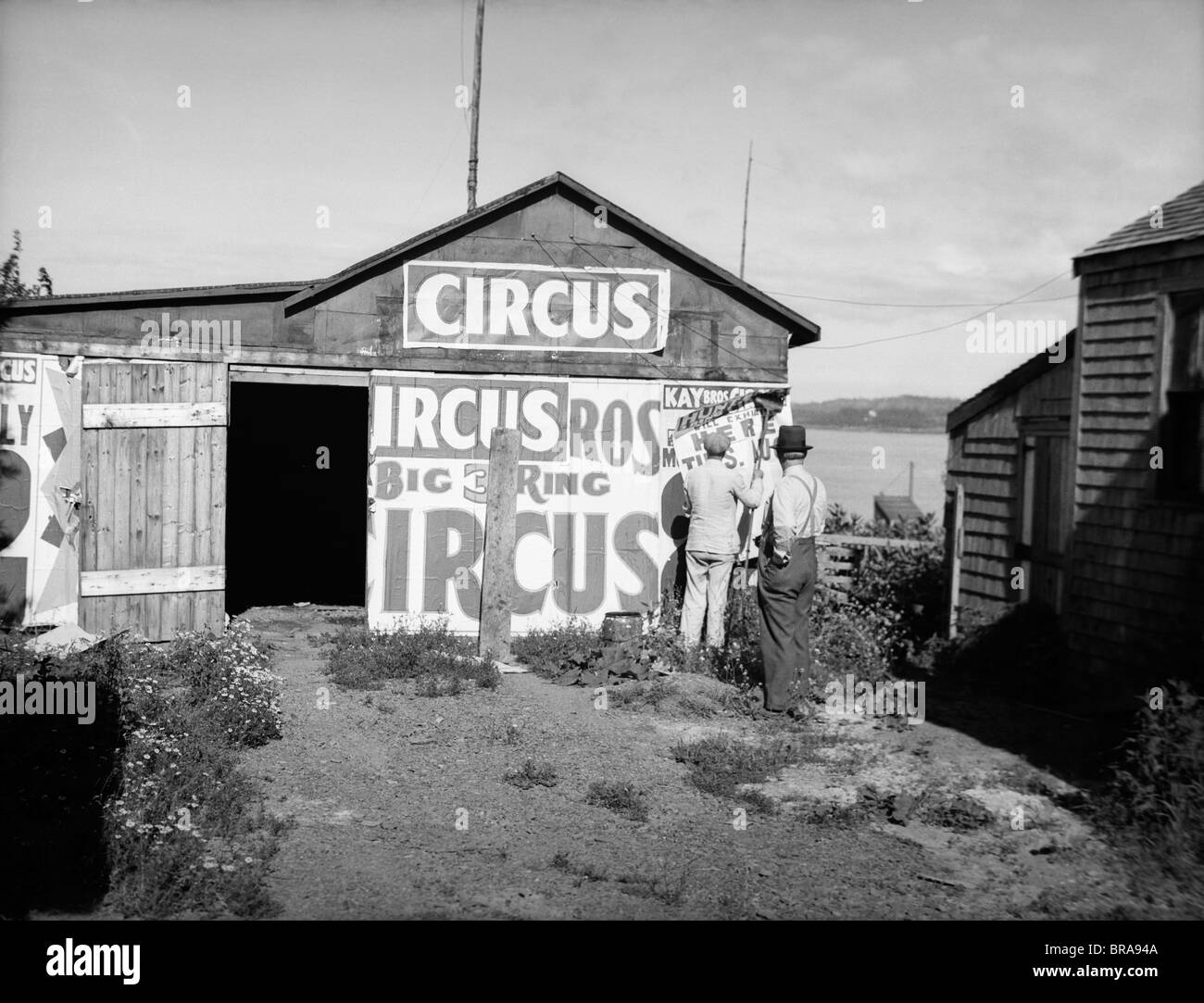 1920s bill posters sticking signs on the side of a barn ...