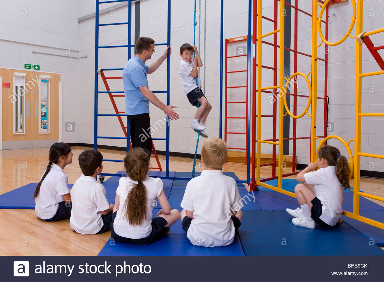 Gym teacher in school gymnasium with students demonstrating rope Stock
