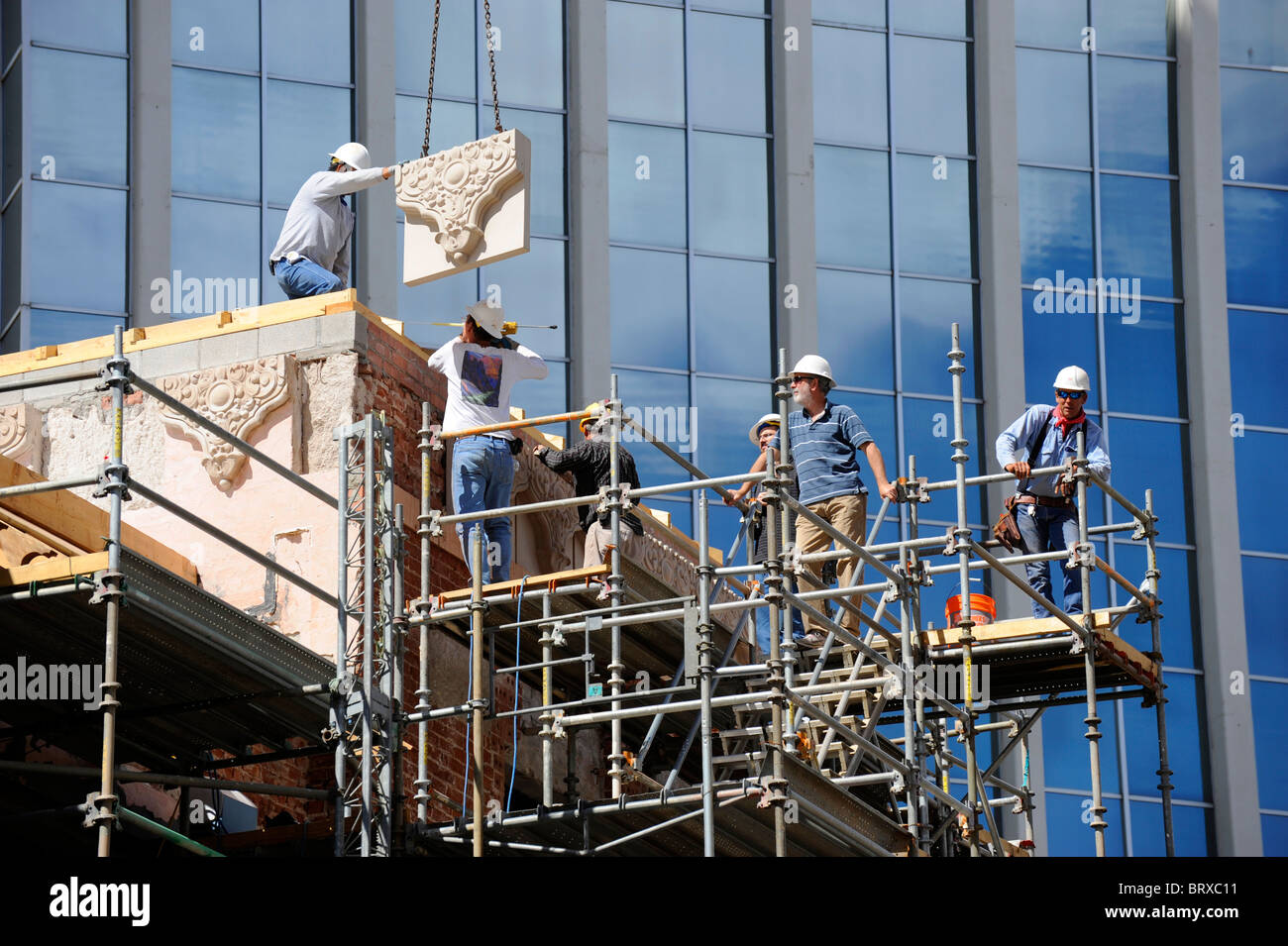 Construction Workers on Scaffolding erect facade using pulley on Stock