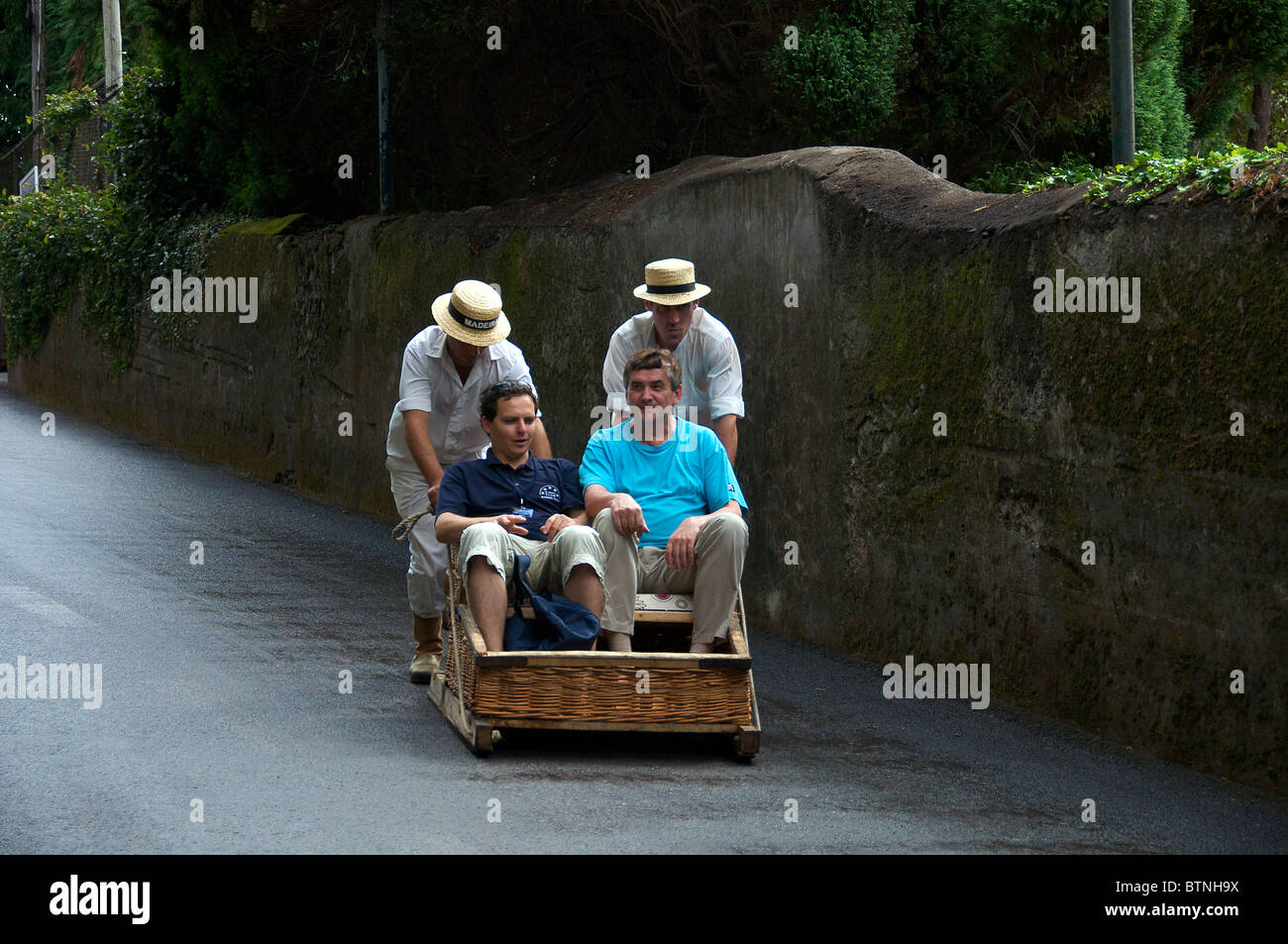 Two men being pushed in wicker toboggan run Monte Funchal Madeira Stock