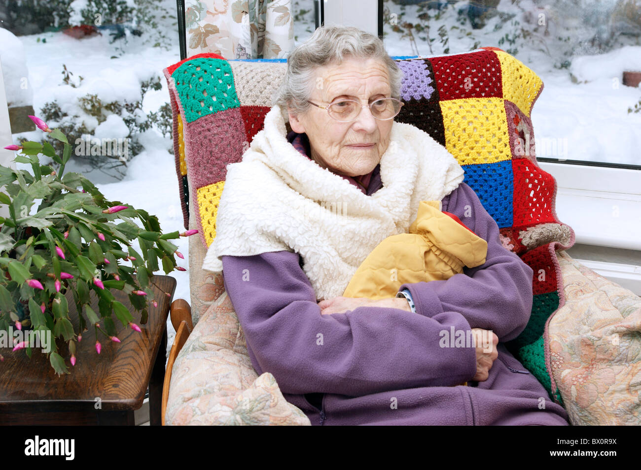 elderly woman keeping warm in winter wrapped up with a fleece blanket