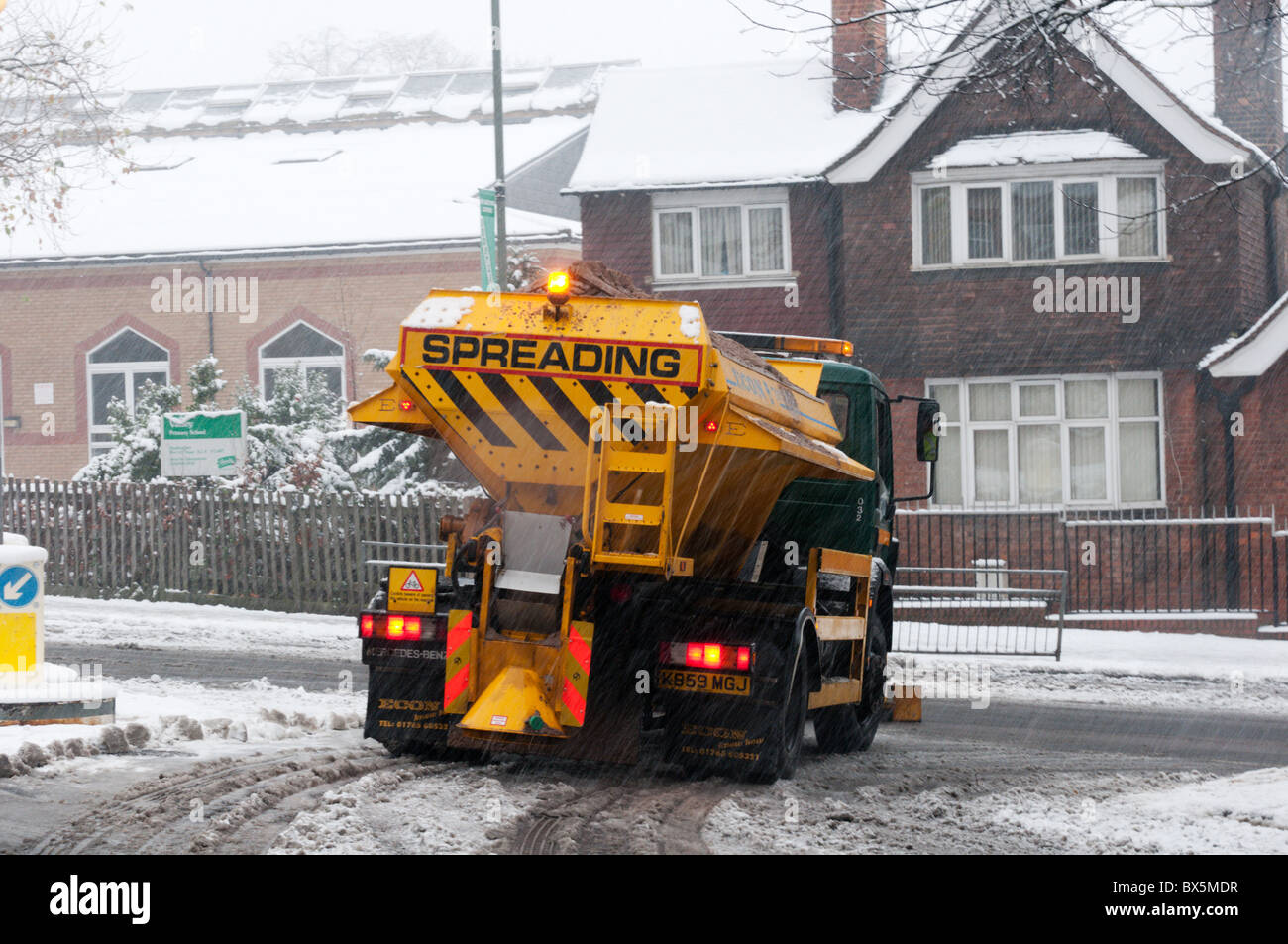 A gritting lorry spreading grit or salt over a suburban road in South