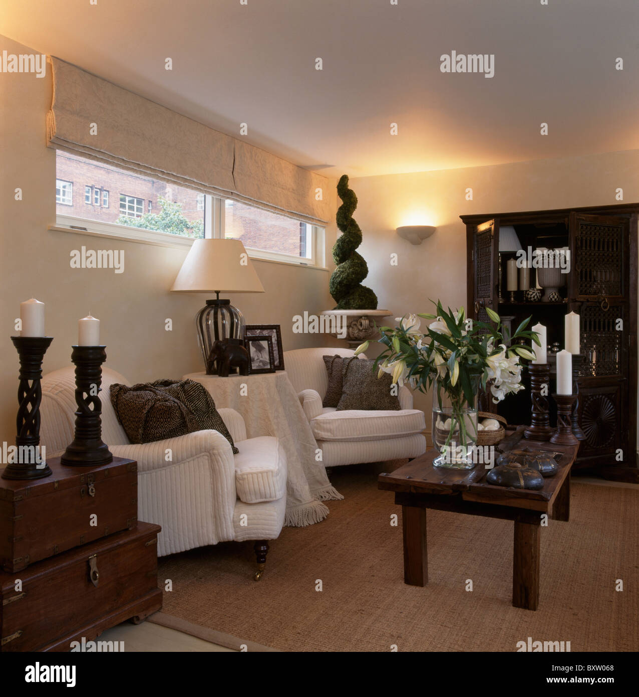 Cream Linen Blinds On Narrow Windows Above White Armchairs In Living Room With Vase Of Lilies Rustic Wood Coffee Table Cream Linen Blinds On Narrow Windows Above White Armchairs In Living Room With Vase Of Lilies Rustic Wood Coffee Table