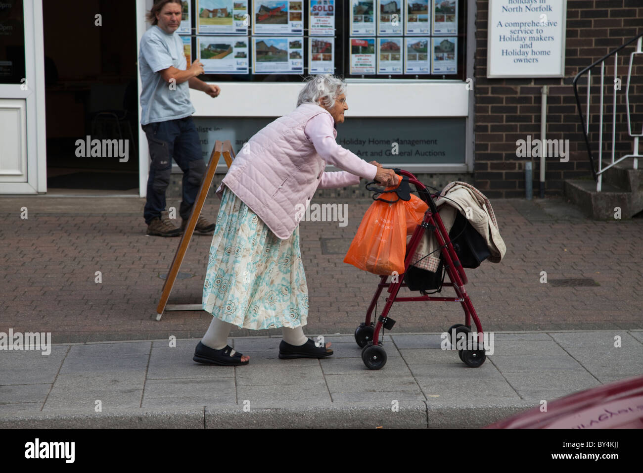old-lady-pushing-a-four-wheel-zimmer-walking-frame-in-sheringham-norfolk-BY4KJJ.jpg