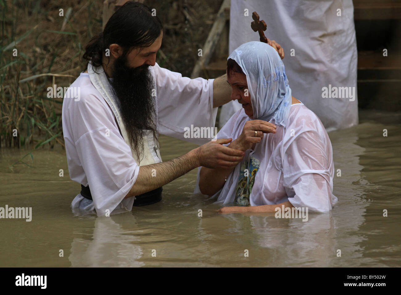 An Eastern Orthodox priest baptize a Christian pilgrim at the Stock