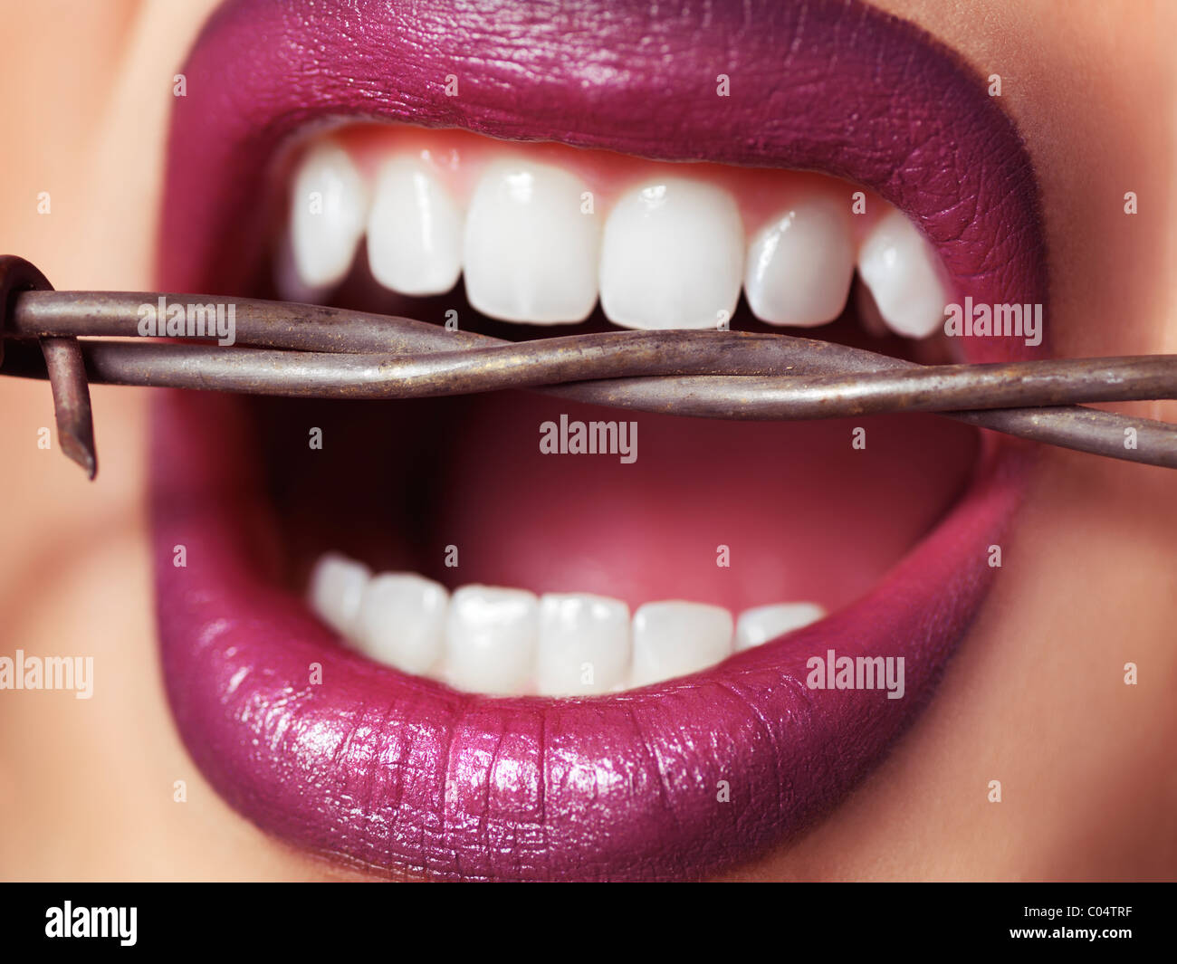 Closeup of woman's mouth with strong healthy teeth biting into barbed