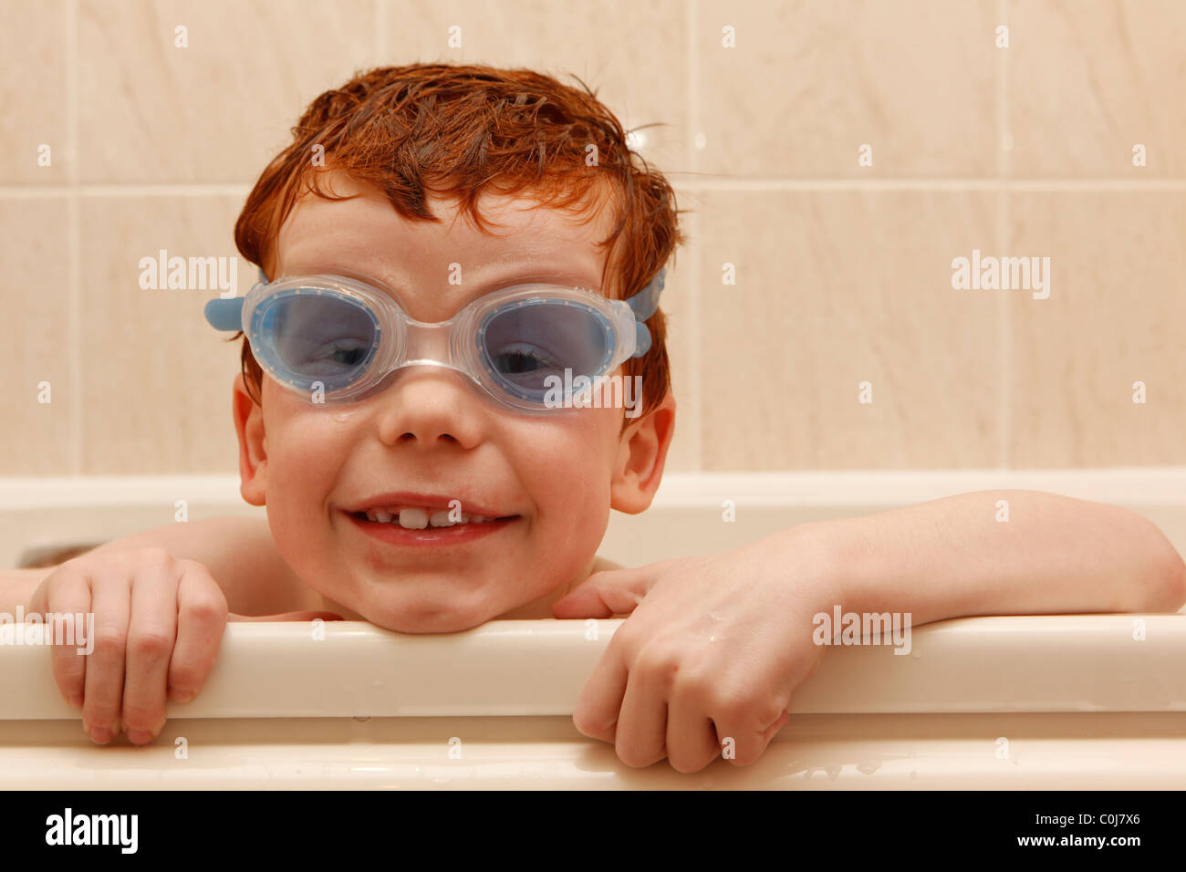 Aged seven little boy wearing goggles whilst playing in the bath Stock