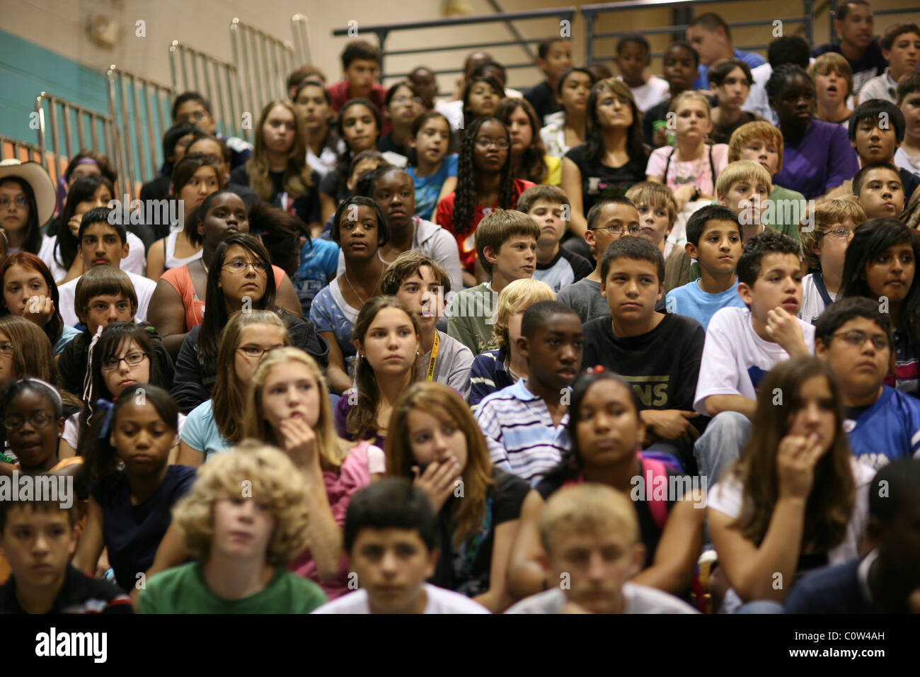 Middle school students sit on bleachers in school gymnasium to watch