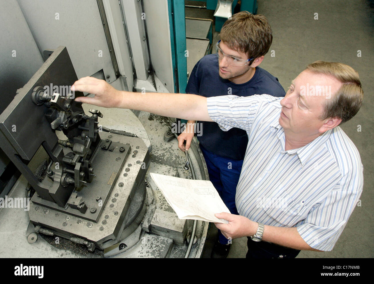 A training supervisor showing an industrial mechanic apprentice how