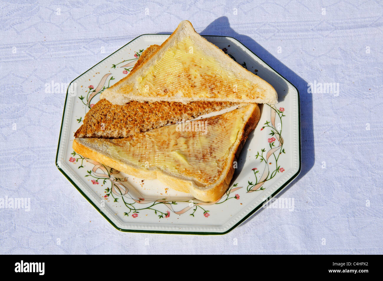 Buttered toasted white and wholemeal bread on an octagonal plate Stock