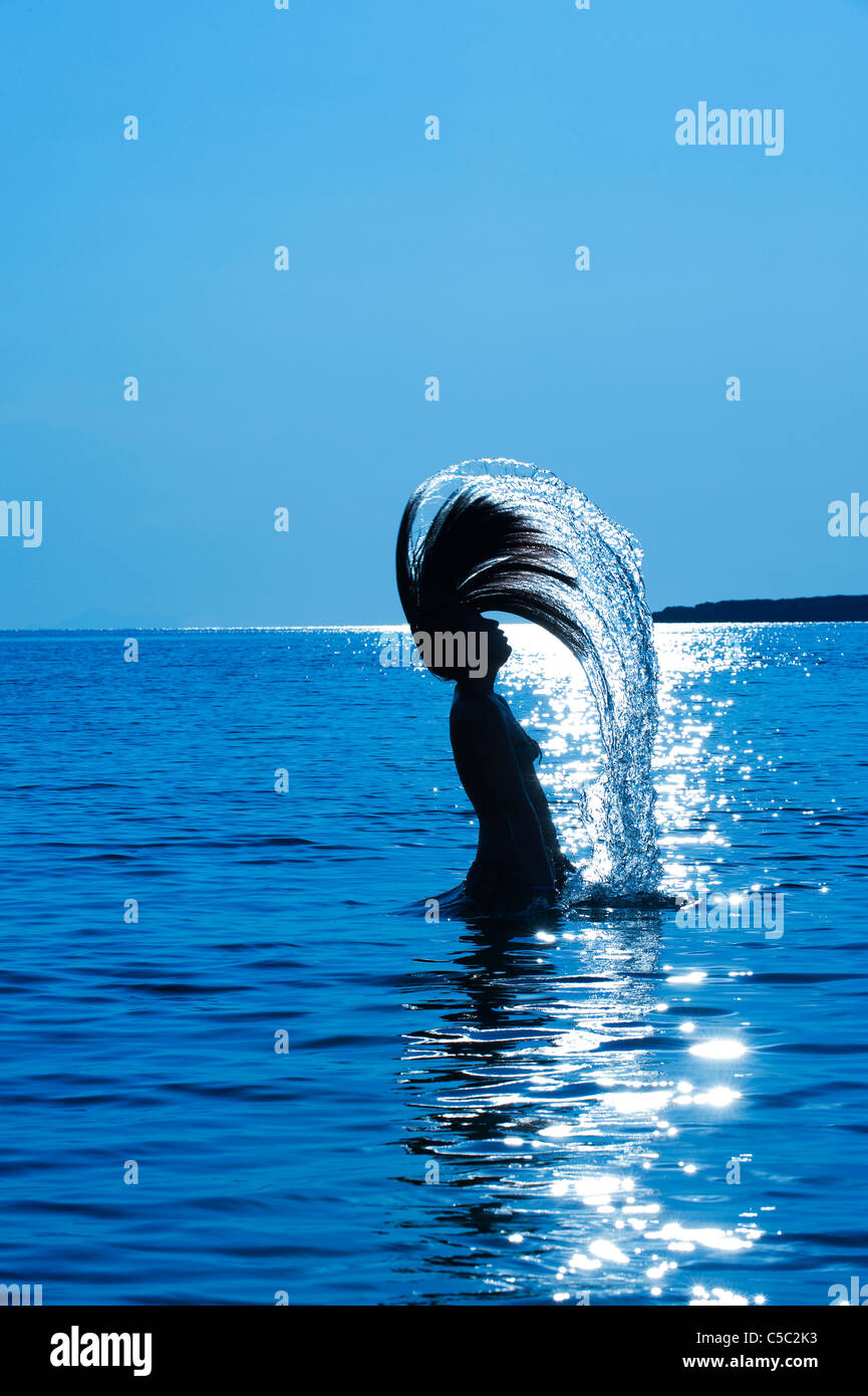 Side view of a silhouette teenage girl throws back her wet hair in