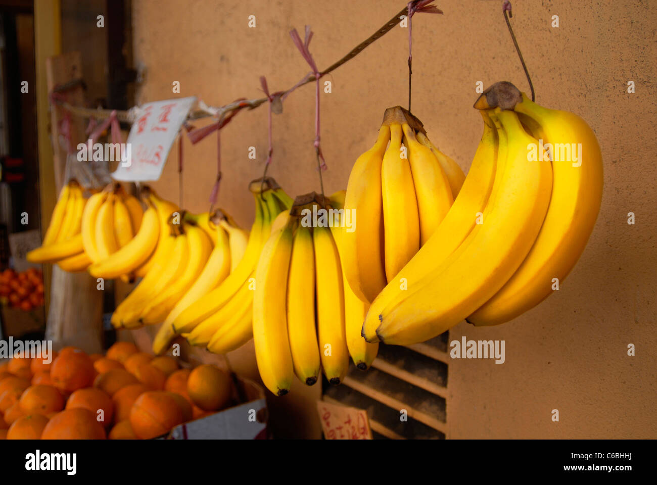 Several bunch of bananas hang from a Chinese market where they are
