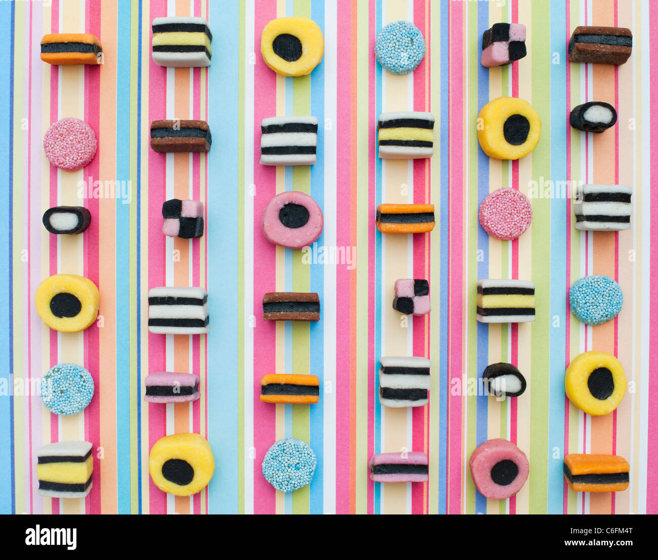 Liquorice allsorts on a multicoloured striped background Stock Photo