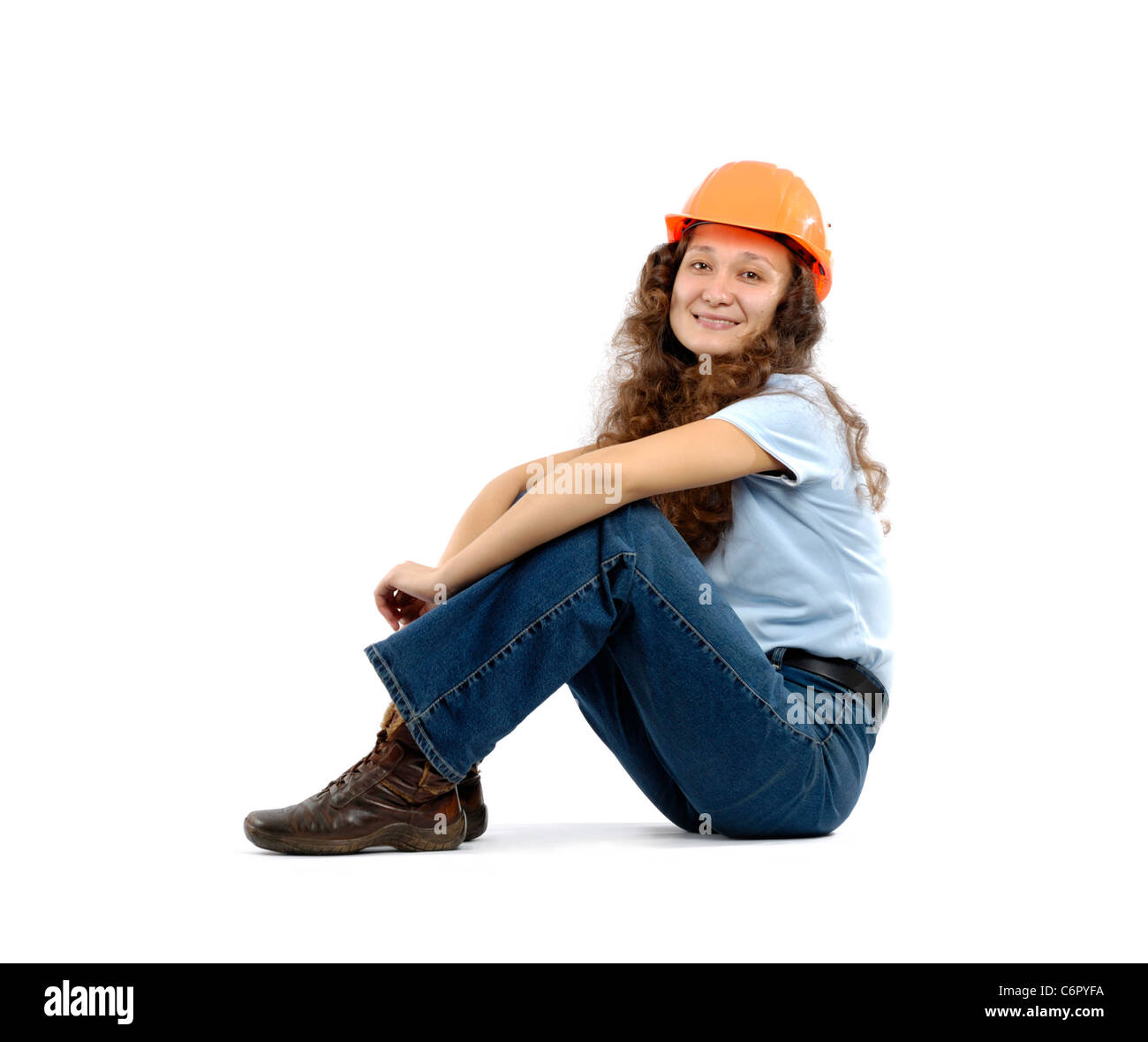Pretty young woman in a hard hat sitting isolated on white Stock Photo