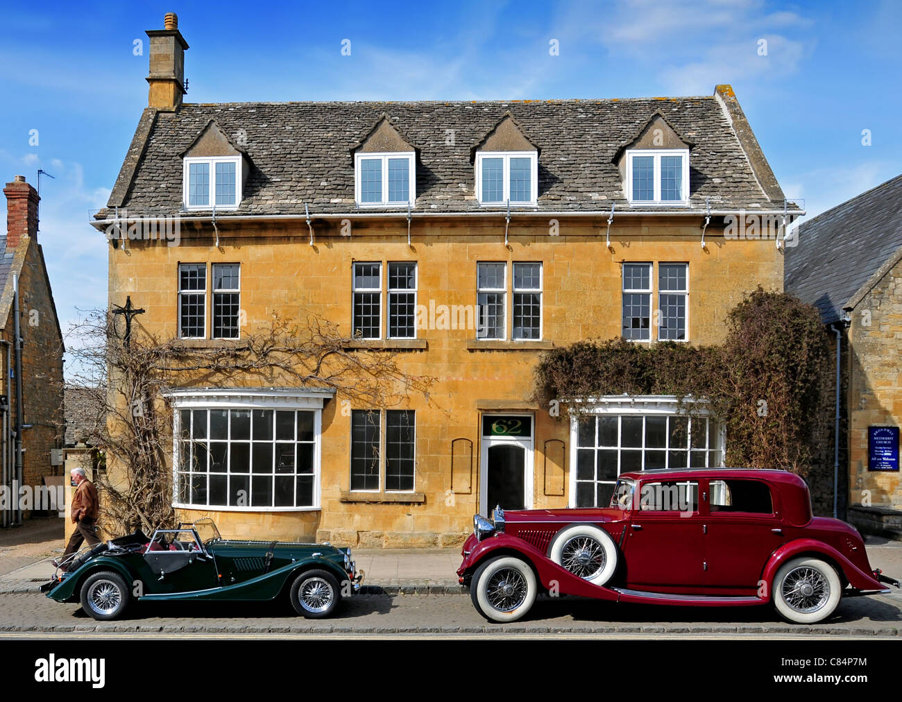 Two classic cars parked outside a historic building, Broadway Stock