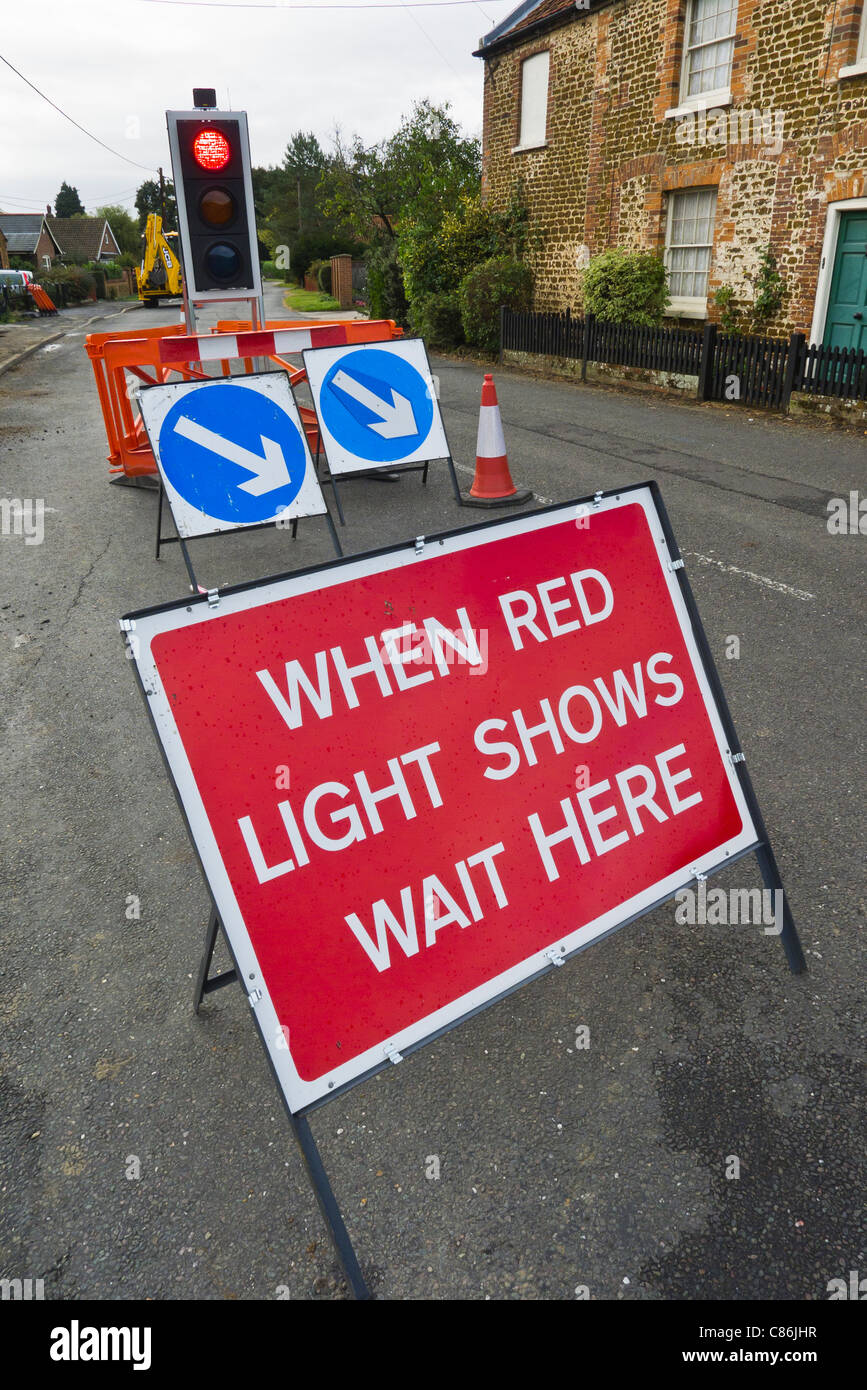 Traffic lights at roadworks with a sign saying "WAIT HERE WHEN RED Stock Photo, Royalty Free
