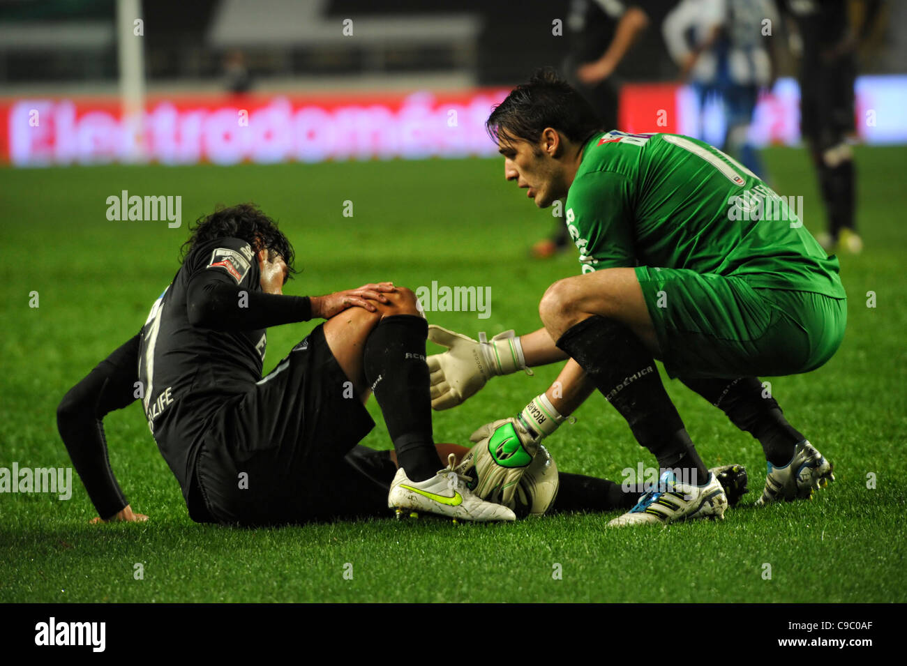 Goalkeeper helping an injured football player get up from the pitch