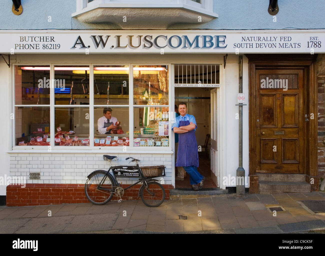 Butcher standing outside butchers shop in Totnes, Devon, U.K Stock