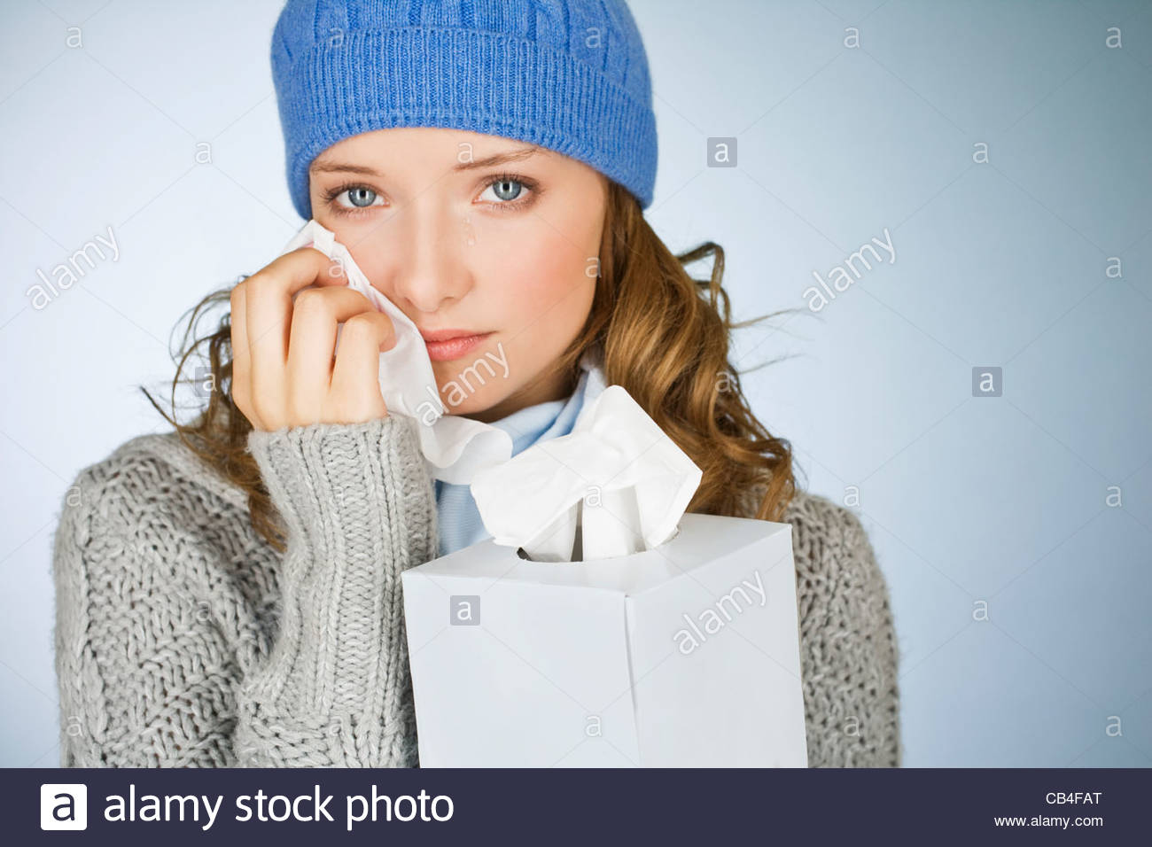 A young woman crying, wiping her tears away with a tissue Stock Photo