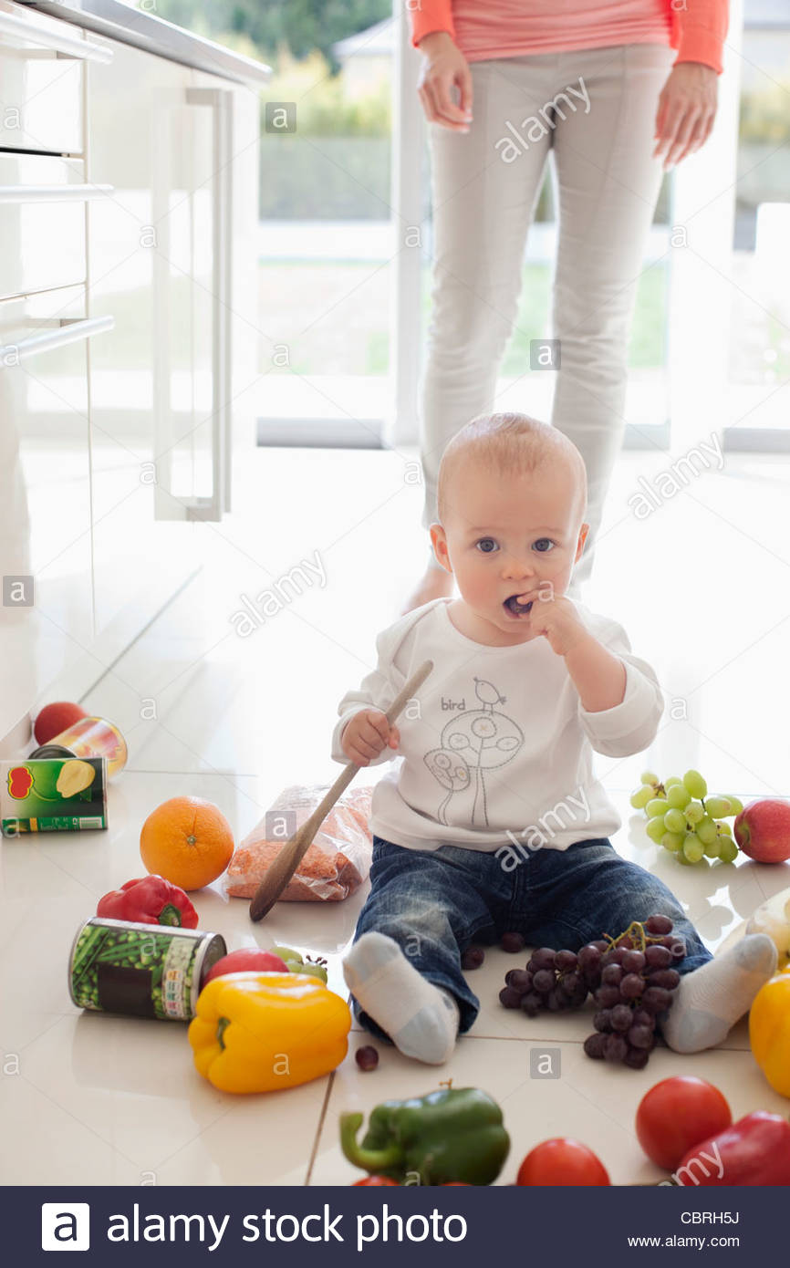 Baby making mess on floor with food Stock Photo, Royalty Free Image