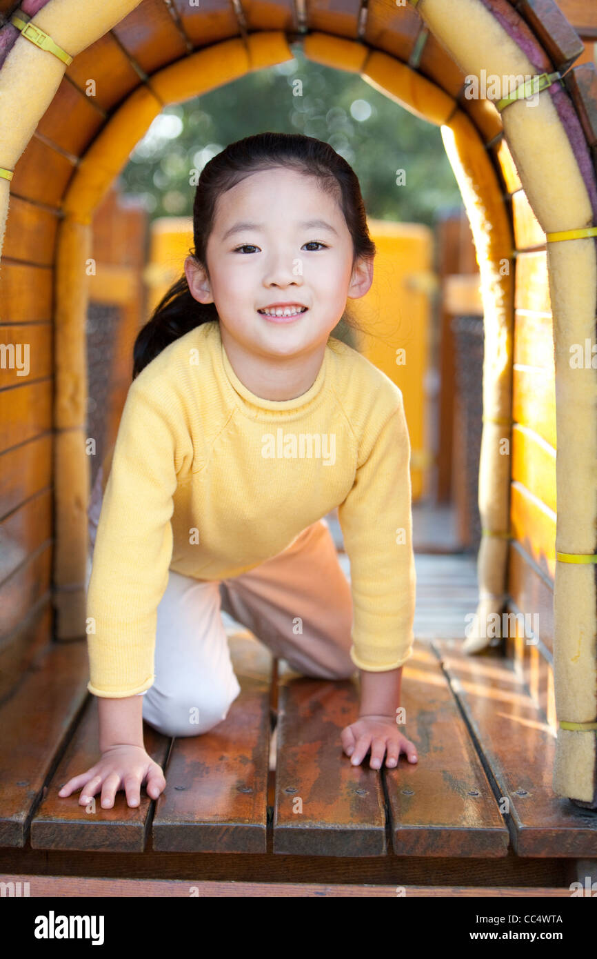 Girl crawling through tunnel in playground Stock Photo, Royalty Free