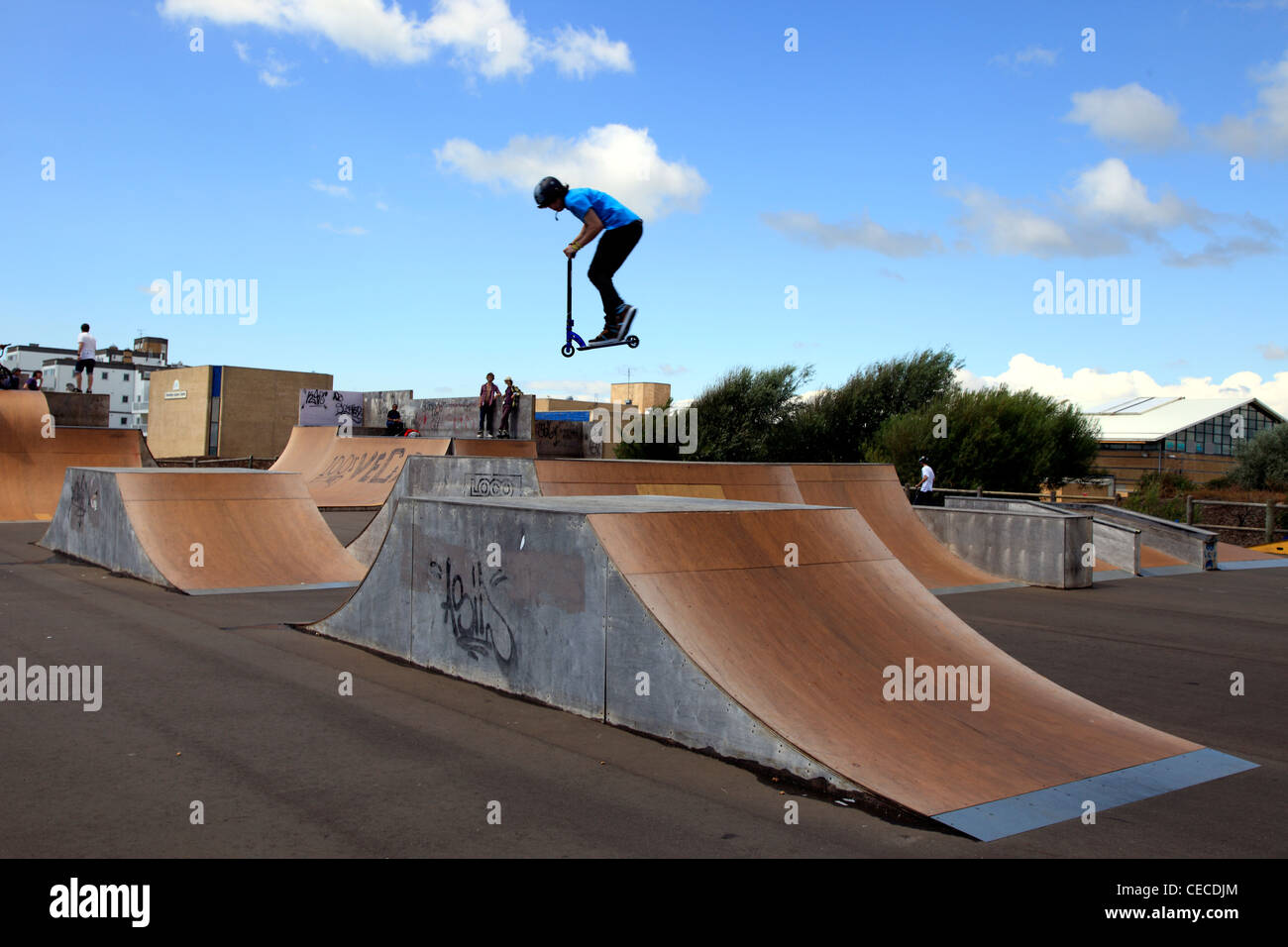 Youth on a scooter jumping from a jump ramp at the seafront Stock Photo