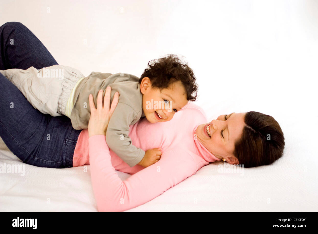 Female Brunette Hair Wearing Pink Poloneck And Blue Jeans Lying On Back Looking Down Smiling