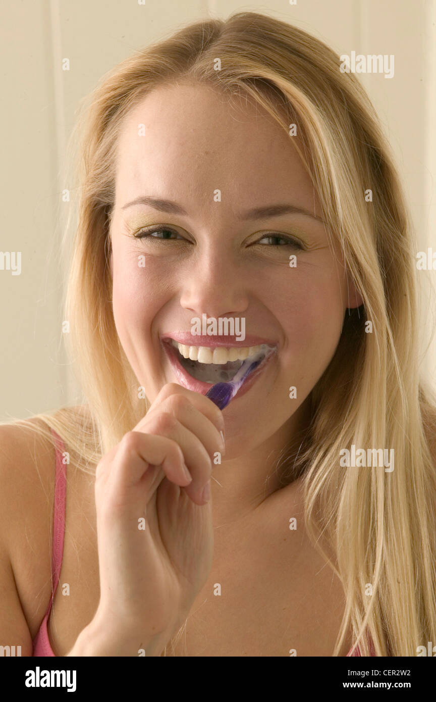 Female Long Blonde Hair Wearing Pink Vest Top Brushing Teeth Purple