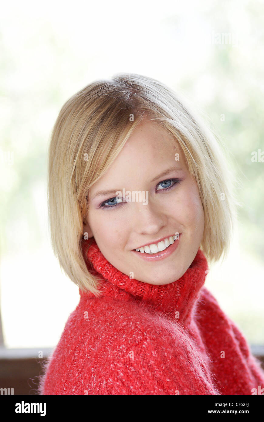 Blonde Female With Bobbed Hair Wearing A Red Polo Neck Jumper Smiling