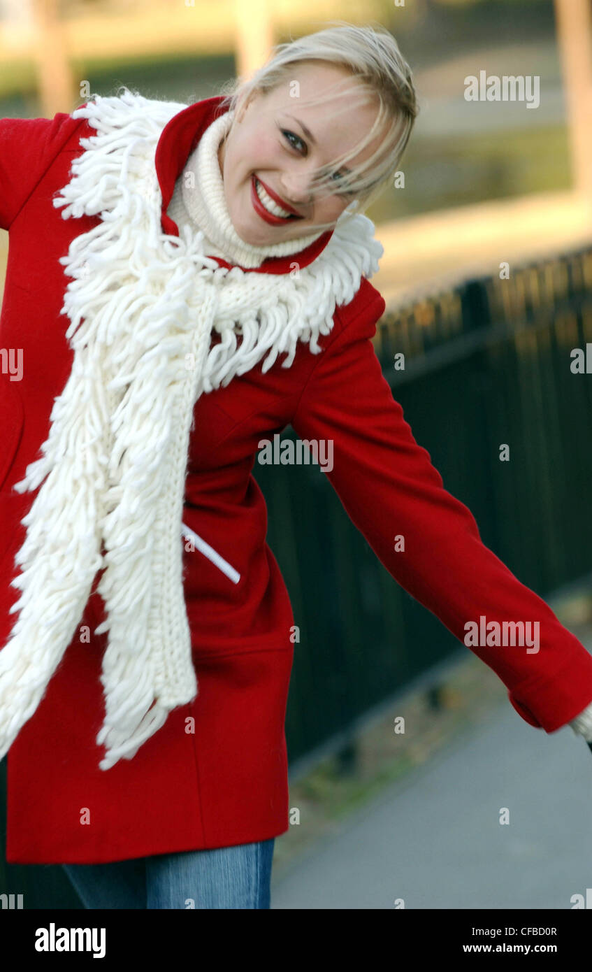 Female Long Blonde Hair Wearing Cream Poloneck Red Coat And Cream Fringed Scarf Walking By