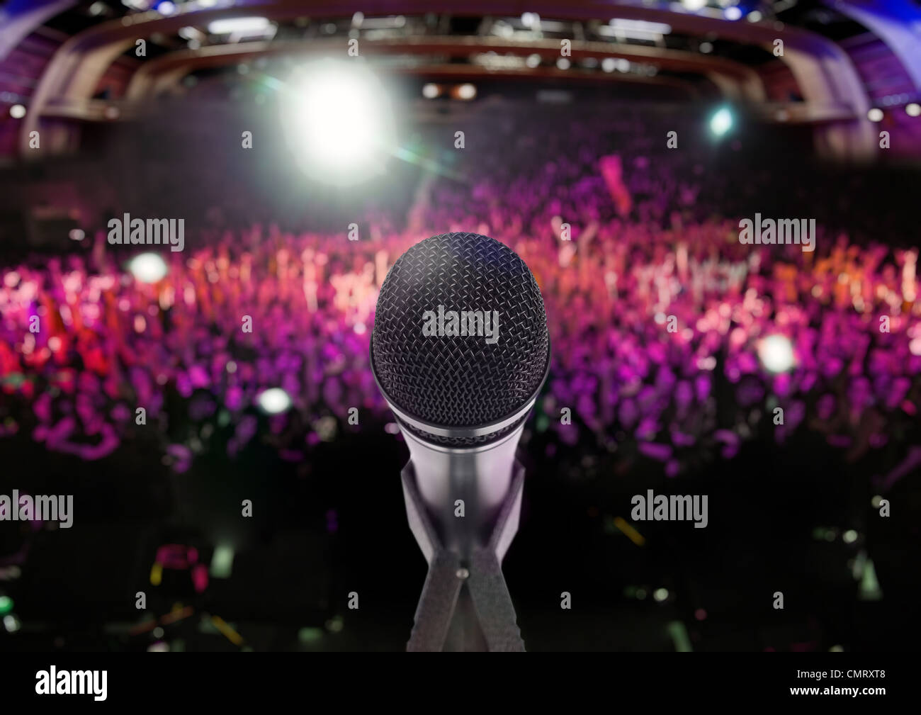 Microphone on stage with an audience on the background Stock Photo