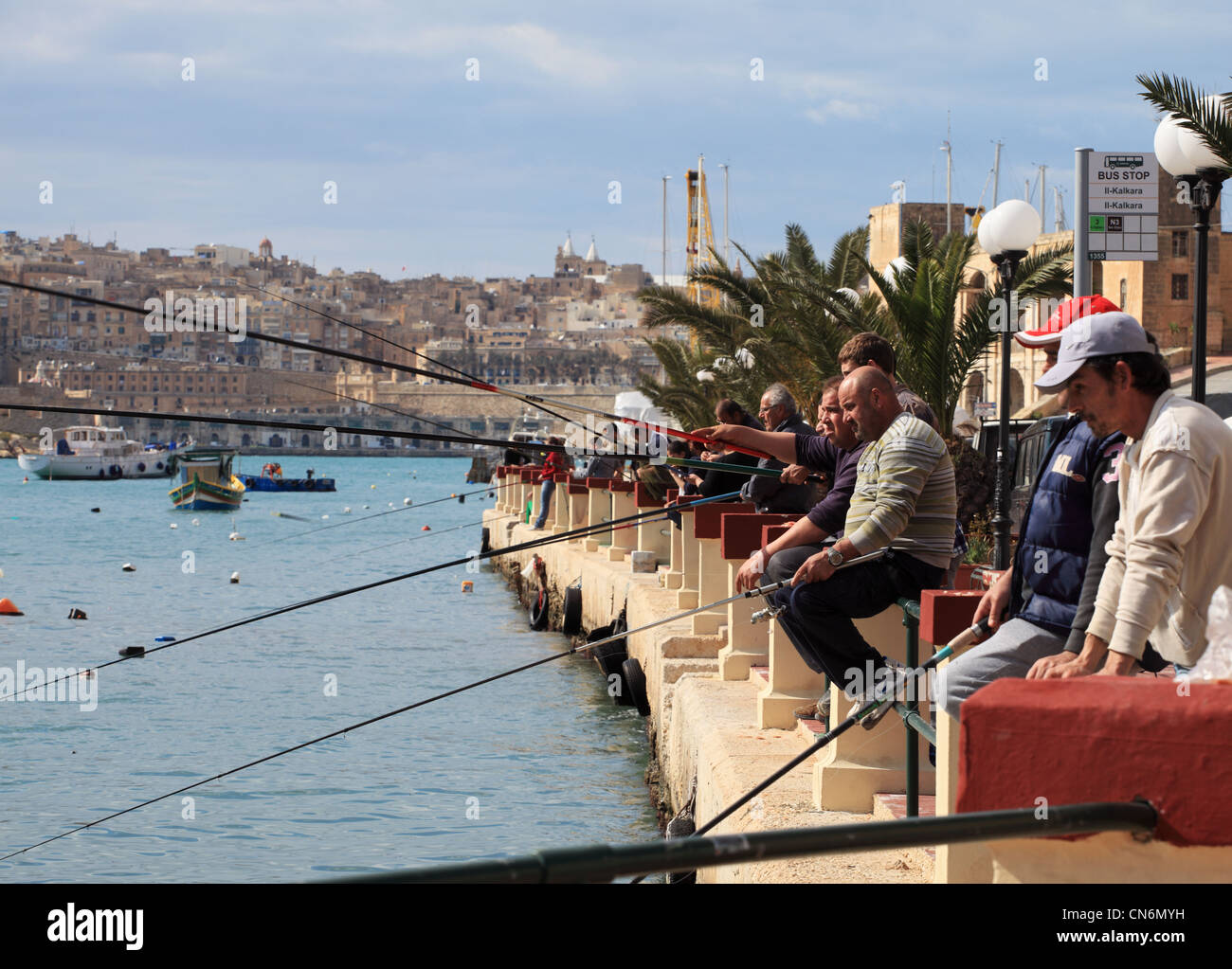 A group of people fishing, using rods and lines, within the harbour