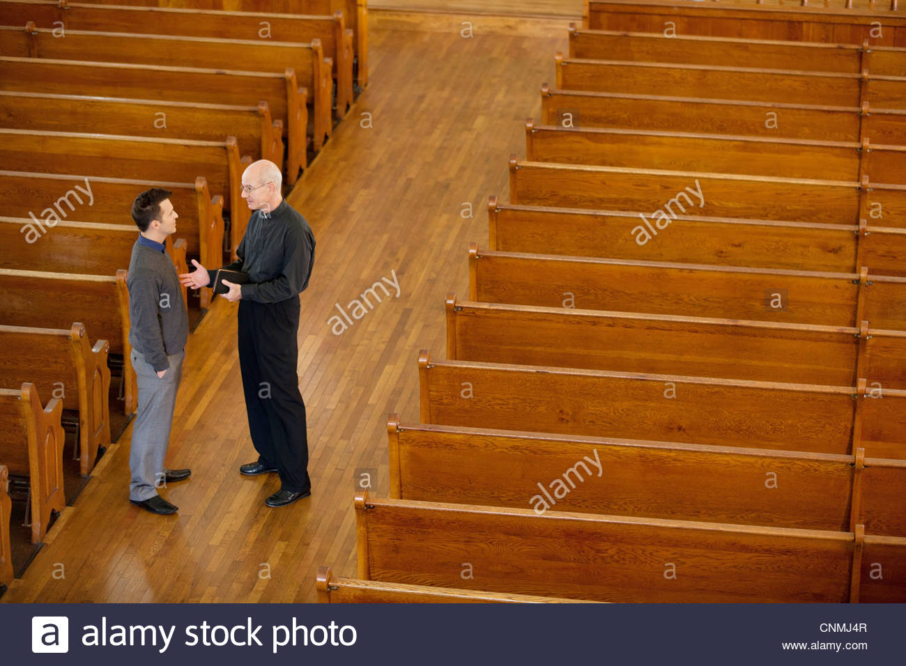 Priest talking with man in church Stock Photo, Royalty Free Image