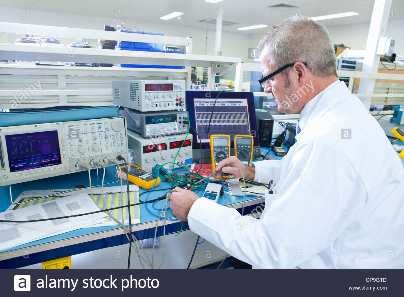 Engineer working at electrical test bench next to oscilloscope Stock