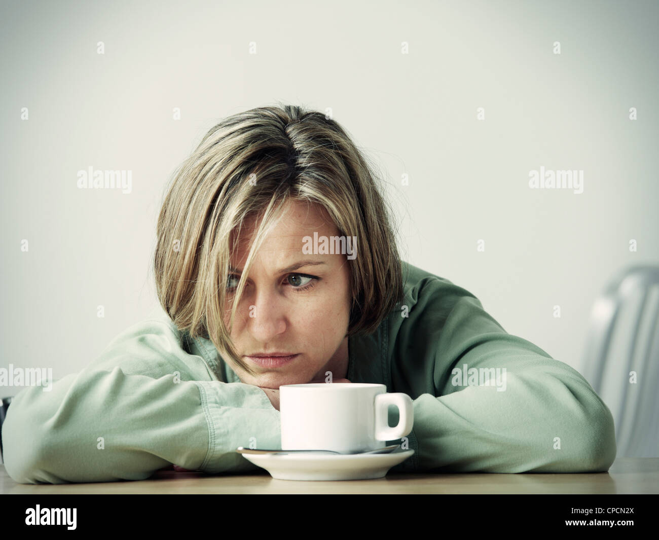 Woman resting head in hands at desk Stock Photo, Royalty Free Image