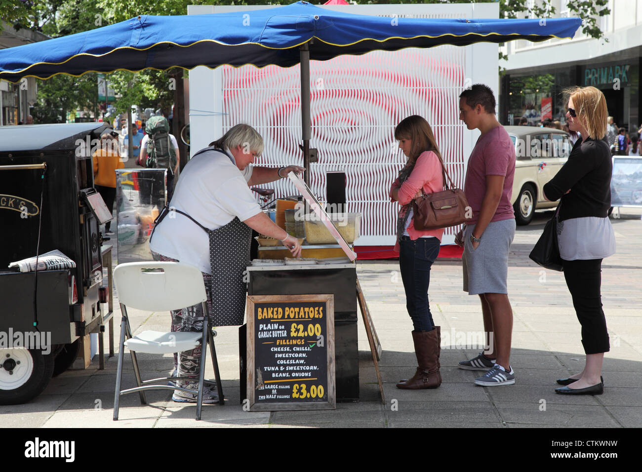 People queuing to buy baked potatoes Portsmouth street market England