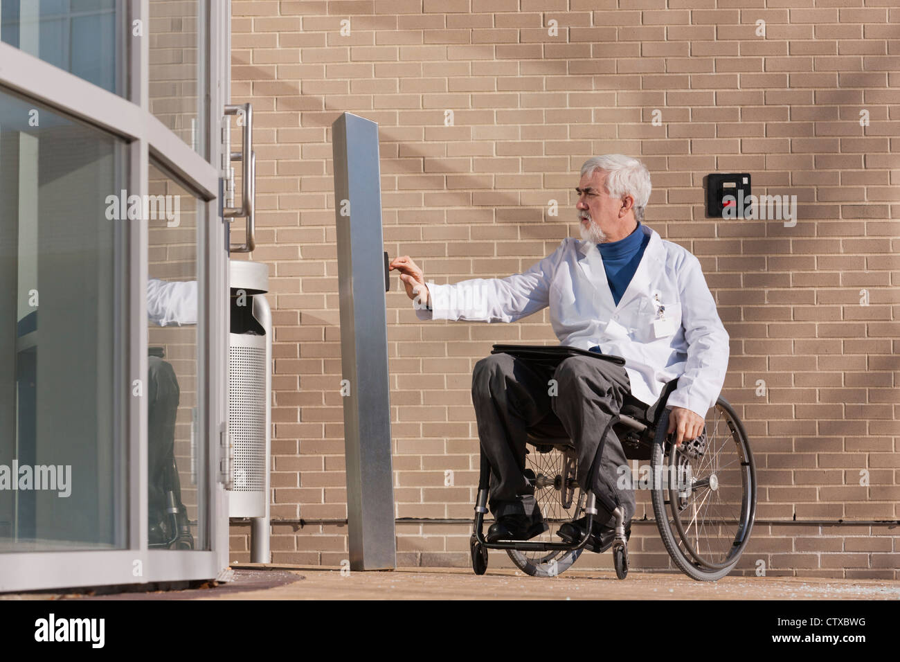 Doctor with muscular dystrophy in wheelchair at hospital entrance Stock