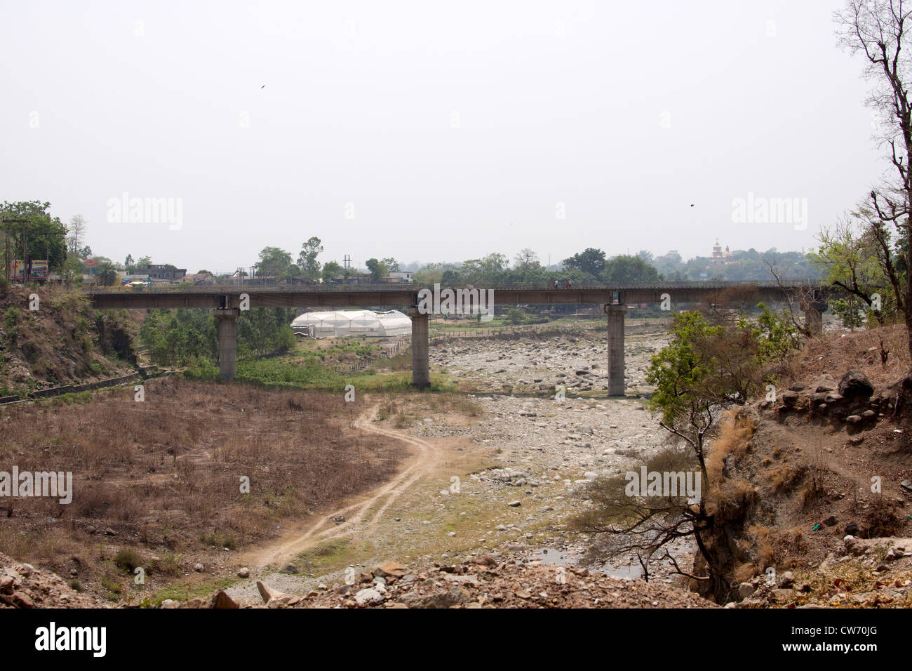 People crossing a bridge over a dry river bed in North India. This