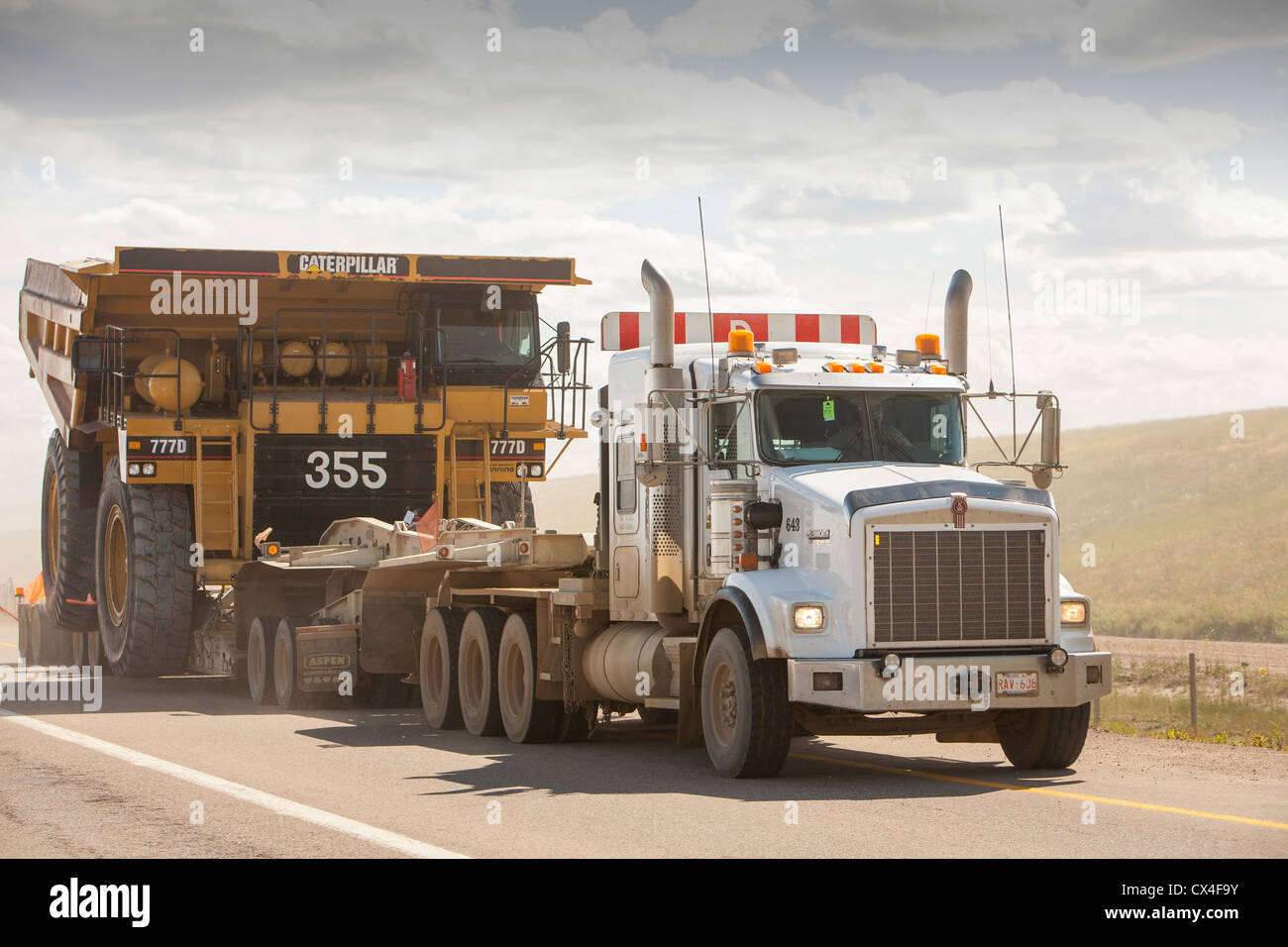 Trucks haul an oversize load, a massive dump truck used in the tar