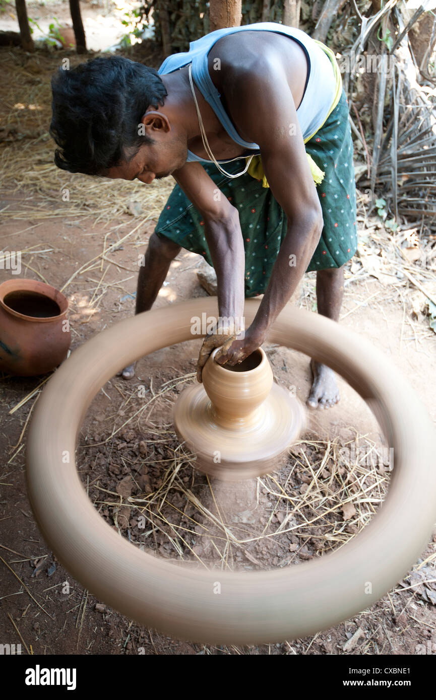 Village potter forming hand made clay pot on potter's wheel spinning Stock Photo, Royalty Free