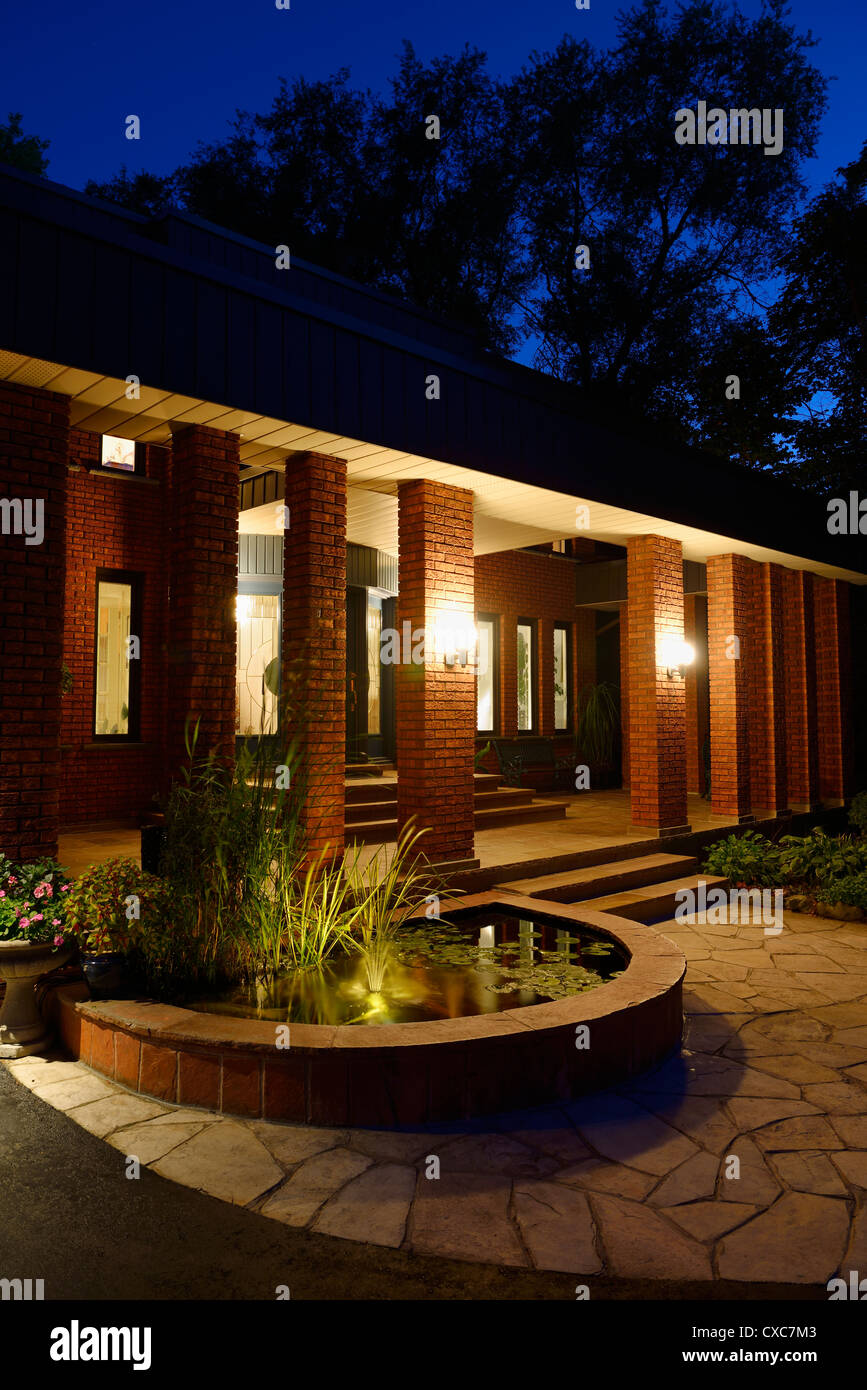 House From Twilight front of a red brick house at twilight with pond pillars and stone House From Twilight front of a red brick house at twilight with pond pillars and stone