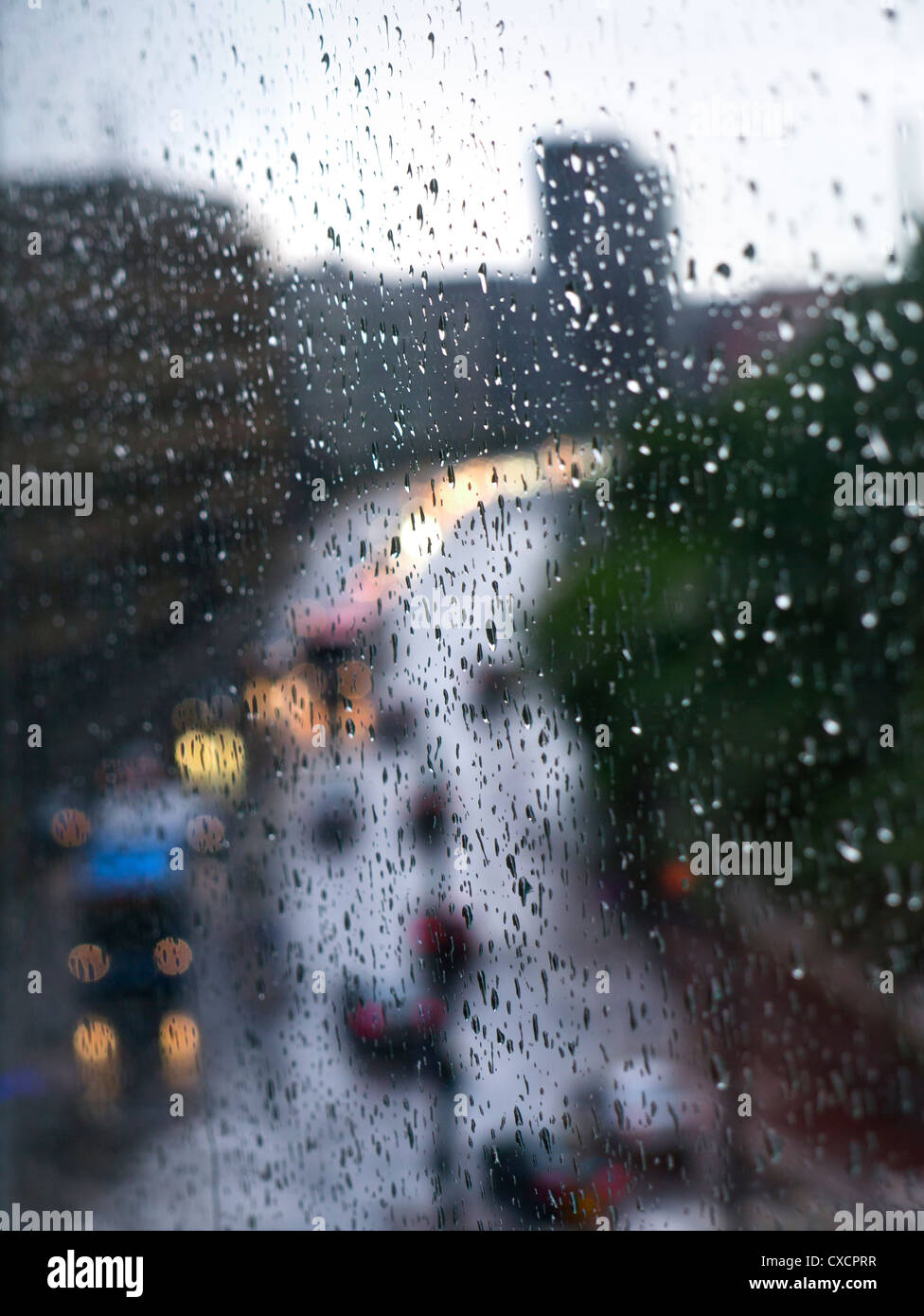 View of rain drops on high rise apartment block window with traffic Stock Photo, Royalty Free