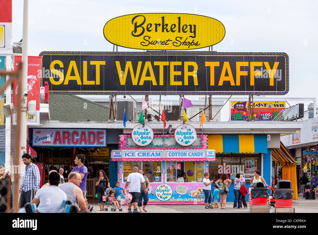 People walking on an ocean boardwalk by a salt water taffy store Stock