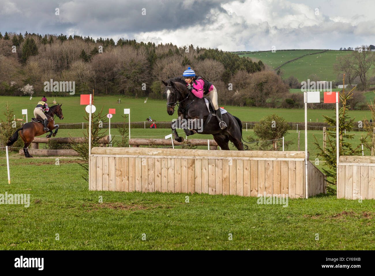 RIDERS AND HORSES JUMPING FENCES AT A CROSS COUNTRY EVENT IN CHEPSTOW