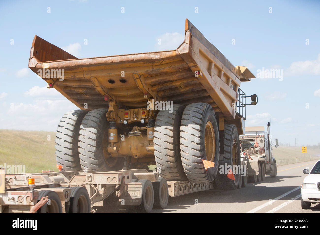 Trucks haul an oversize load, a massive dump truck used in the tar