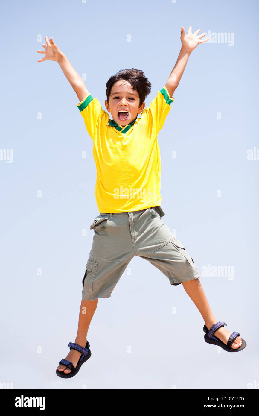 Smart kid jumping high in air, arms stretched and looking at camera