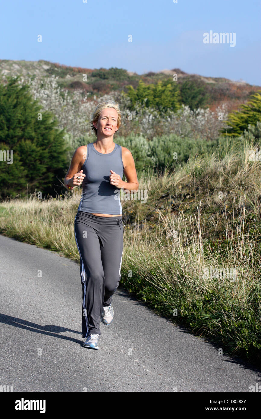 Blonde Woman Outdoors Jogging Along Country Road Stock Photo Alamy