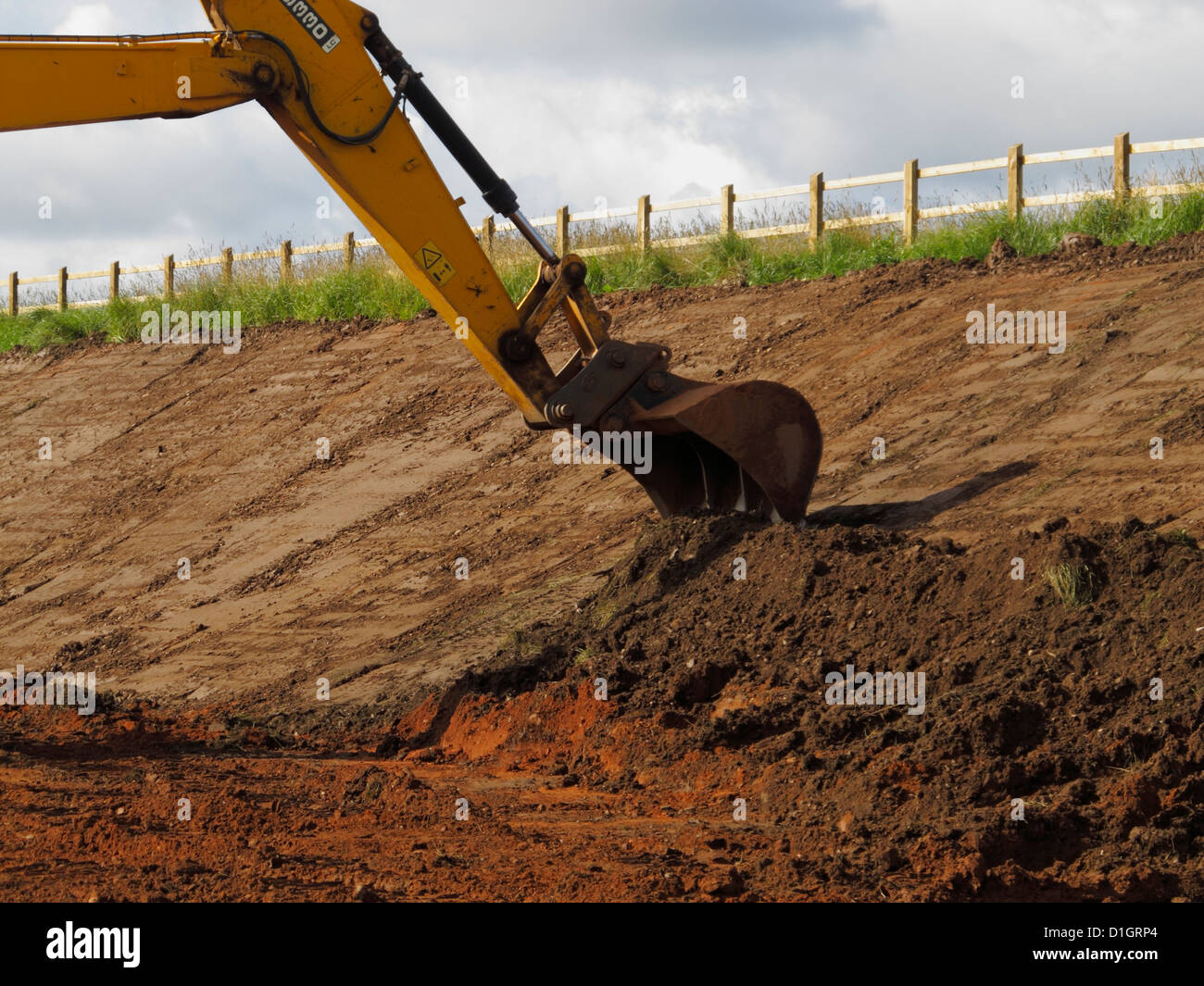 Bucket of large tracked digger excacator trimming cutting slope on
