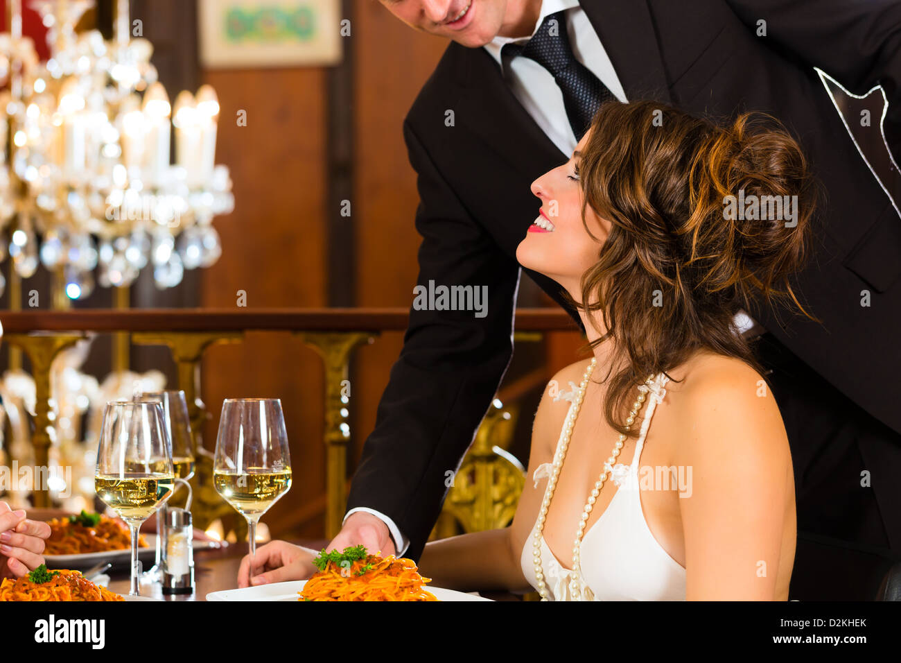 Pretty woman sitting at a table in a fine dining restaurant, waiter
