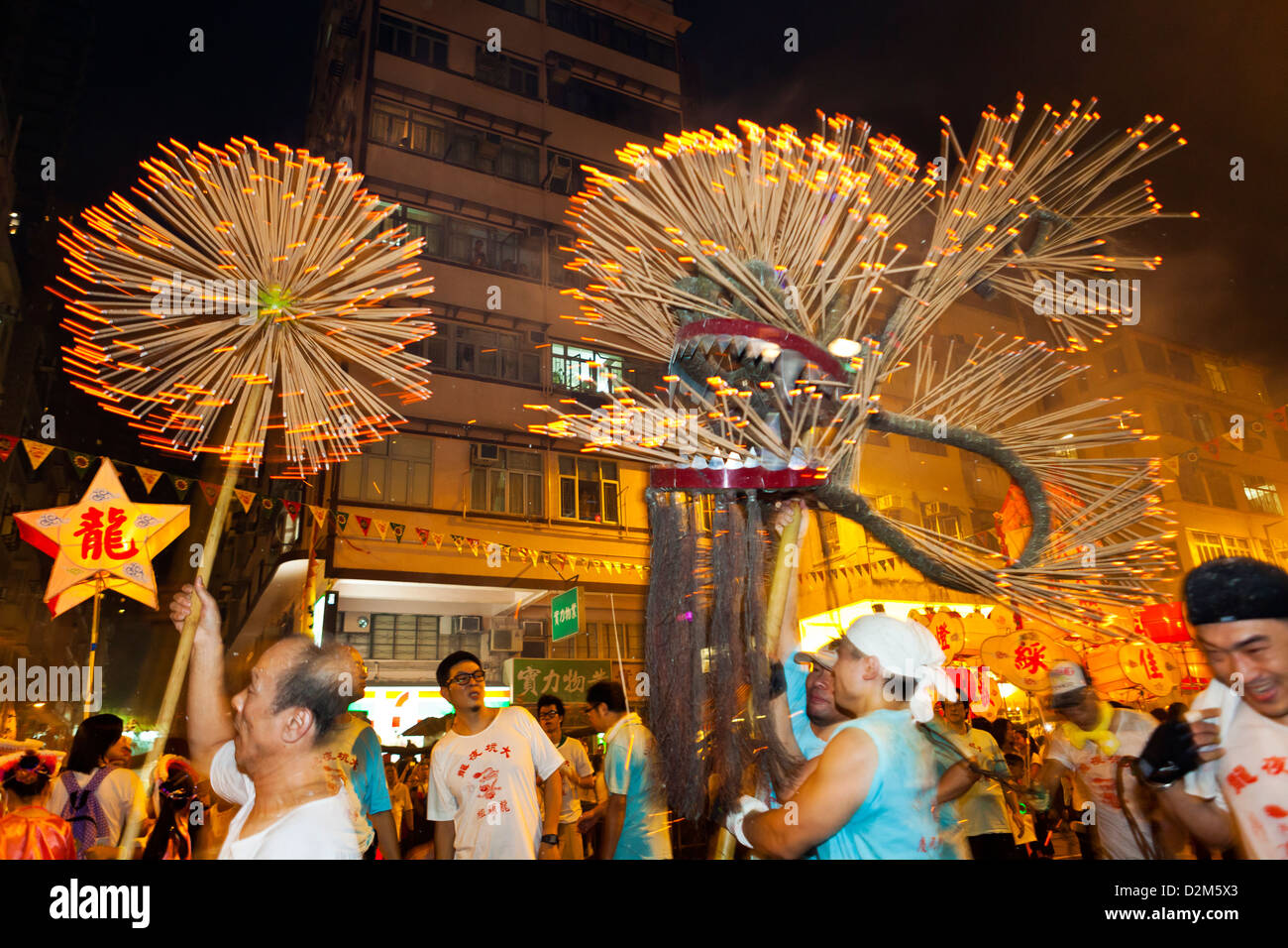 Festive participants celebrate traditional customs in Hong Kong, featuring a vibrant procession with a dragon-like figure and sparklers lighting up the night.